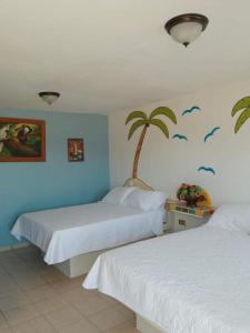 a bedroom with two beds and a palm tree on the wall at Hotel Casa Victoria in Puerto Peñasco