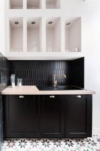 uma cozinha com armários pretos e um lavatório em Le 107Chinon em Chinon