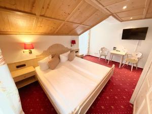 a bedroom with a large bed and a table at Hotel JMS Holiday Allgäu in Oberreute