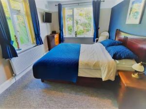 a bedroom with a bed with blue walls and windows at Brixham View House in Torquay