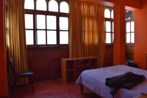 um quarto com uma cama, uma secretária e janelas em Casa a 3 cuadras de la plaza de armas Huamanga em Ayacucho