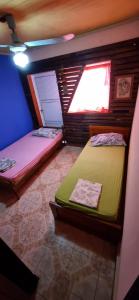 2 camas en una habitación con ventana en Paz alojamiento en Jardín América