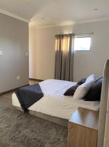 a bedroom with a large bed with a window at Stunning gem by OR Tambo Airport in Benoni