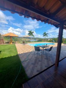 Un patio con mesa y sillas y una piscina. en Rancho Paraíso, en Capitólio