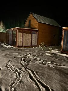 a house with footprints in the snow on a street at Domki trzy jeziora z zewnętrznym SPA - sauna, balia do schładzania i jacuzzi in Małe Swornegacie