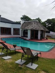 a pool with two chairs and a house at Unique Guest House in Hallack Rock