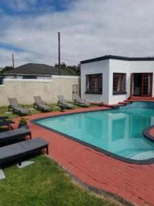 a swimming pool with chairs and a building at Unique Guest House in Hallack Rock