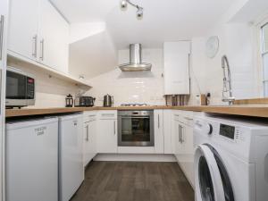 a kitchen with white cabinets and a washer and dryer at Swallow Cottage in Herne Bay