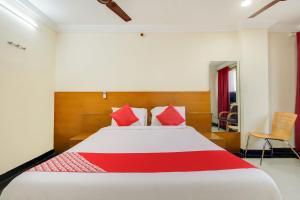 1 dormitorio con 1 cama grande con almohadas rojas en OYO Srinivasa Residency en Tirupati