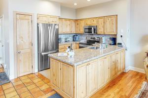 a kitchen with wooden cabinets and a stainless steel refrigerator at The Village Ski In Ski Out in Beaver Creek