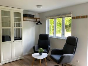 uma sala de estar com duas cadeiras e uma mesa em Cozy private annex near bathing lake and 30 min. from Copenhagen em Slangerup