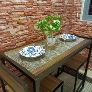 una mesa de madera con platos y vasos. en 1BR Aesthetic Condotel with Balcony - EDSA en Manila