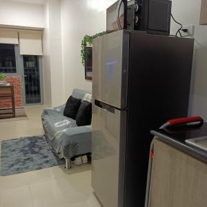 uma cozinha com um frigorífico preto e um sofá em 1BR Aesthetic Condotel with Balcony - EDSA em Manila