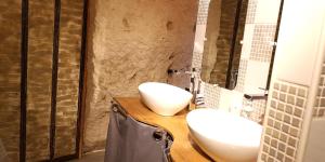 La salle de bains est pourvue de 2 lavabos blancs sur un comptoir en bois. dans l'établissement Troglogîtes de la Tourette, à Les Roches-lʼÉvêque