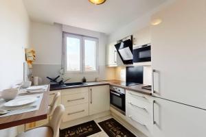 a kitchen with white appliances and a table with chairs at Cosy duplex aux portes de Paris in Maisons-Alfort