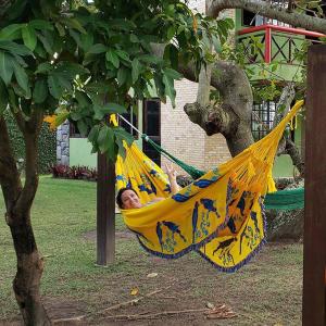 a man laying in a hammock under a tree at Chalé Verde in Tamandaré