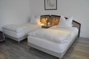 two beds in a hotel room with white pillows at Boardinghaus zu Coburg in Coburg