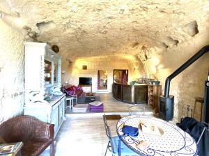 uma sala de estar com uma parede de pedra e uma mesa em Troglogîtes de la Tourette em Les Roches-lʼÉvêque