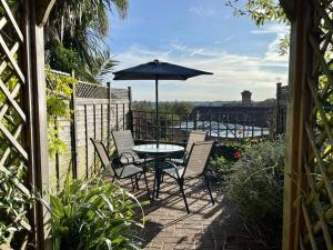 a patio with a table and chairs and an umbrella at Quaint Cottage in the heart of Arundel in Arundel