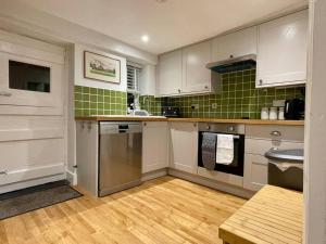 a kitchen with white cabinets and green tile at Quaint Cottage in the heart of Arundel in Arundel