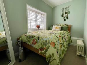 a bedroom with a bed with a floral bedspread and a window at Quaint Cottage in the heart of Arundel in Arundel