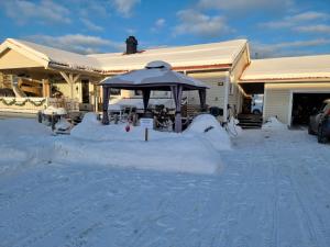 a gazebo in the snow in front of a house at Kjellerleilighet egen inngang. in Stange
