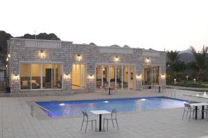 a house with a swimming pool and tables and chairs at إستراحة البيت الحجري in Fulūj Sayghah