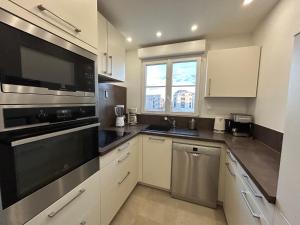 a kitchen with white cabinets and black appliances at Disney 3 mn, 14 people , 4 bedrooms, 2 parkings privés in Chessy