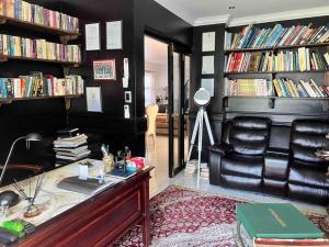 a living room with a leather chair and book shelves at Apartment on 32 in Cape Town