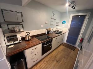 cocina con armarios blancos y encimera de madera en Cosy North Wales 2 BEDROOM Chalet en Caernarfon