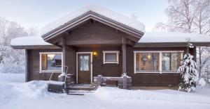una pequeña casa de madera con nieve en el porche en Rukan Talvihovit, en Ruka