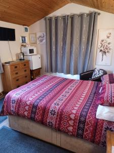 a bedroom with a bed with a red comforter at Dunroaming Cabin in Pendine