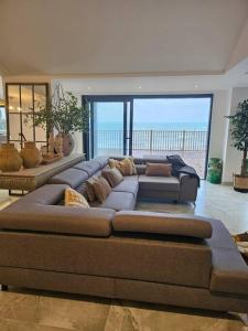 a large couch in a living room with the ocean at Stunning Front Line Ocean Views Luxury Beach House in Downderry