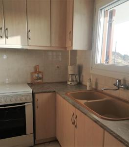 a kitchen with wooden cabinets and a sink and a window at MarGeo View House in Mpatsi, Andros in Batsi
