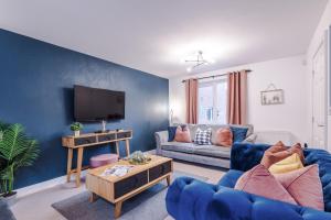 un soggiorno blu con divano e TV di Beautiful Stoke Home Sleeps 10 by PureStay Short Lets a Stoke on Trent