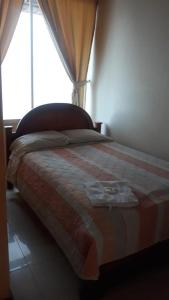 a bedroom with a bed with a blanket and a window at Hotel Mirador Sacha in La Joya de los Sachas