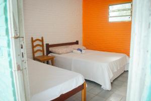 a room with two beds and a chair and a window at Brisa do Mar Hotel in Arroio do Sal
