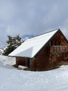 Cabaña de madera con nieve en el techo en Chalet Bastilor, en La Joue du Loup