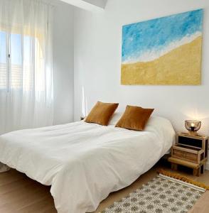 een slaapkamer met een wit bed en een schilderij aan de muur bij Maravilloso apartamento en el centro in Ceuta