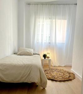 een witte slaapkamer met een bed en een raam bij Maravilloso apartamento en el centro in Ceuta
