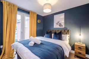 a bedroom with a large bed with blue walls at Beautiful Stoke Home Sleeps 10 by PureStay Short Lets in Stoke on Trent