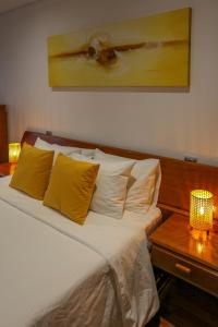Un dormitorio con una cama con almohadas amarillas y una mesa. en Aromas Flavors Tours Esmoriz Beach, en Esmoriz