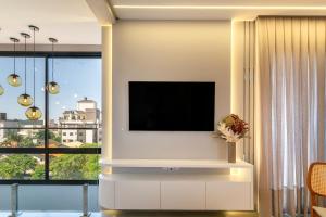 ein Wohnzimmer mit einem Flachbild-TV an der Wand in der Unterkunft Paradise 205 - Cobertura 2 suítes com vista para o mar de dentro e mar de fora na praia do Canto Grande in Bombinhas