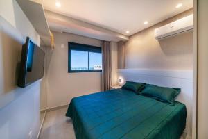 ein Schlafzimmer mit einem grünen Bett und einem TV in der Unterkunft Paradise 205 - Cobertura 2 suítes com vista para o mar de dentro e mar de fora na praia do Canto Grande in Bombinhas