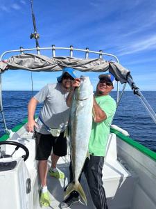 two men on a boat holding a large fish at Casa rodante los cachorones in Loreto