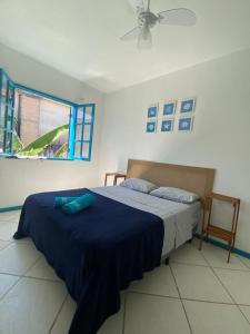 a bedroom with a bed with blue sheets and a window at Pousada do Mar in Arraial do Cabo