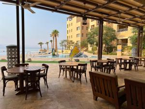 a patio with tables and chairs and a view of the ocean at EP1 TWO BEDROOM APARTMENT AT Samarah Resort in Sowayma