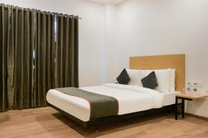 een slaapkamer met een groot bed, een bureau en gordijnen bij Super Townhouse 217 The Awadh Airport Near Chaudhary Charan Singh International Airport in Bijnaur