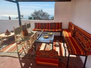 een balkon met een bank, een tafel en een tafel bij Superbe appartement , grande terrasse vue mer et montagne Taghazout in Taghazout