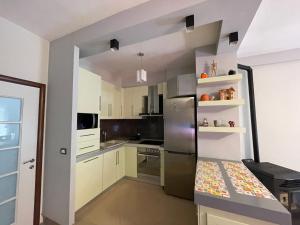 a kitchen with white cabinets and a stainless steel refrigerator at Downtown Apartment in Korçë